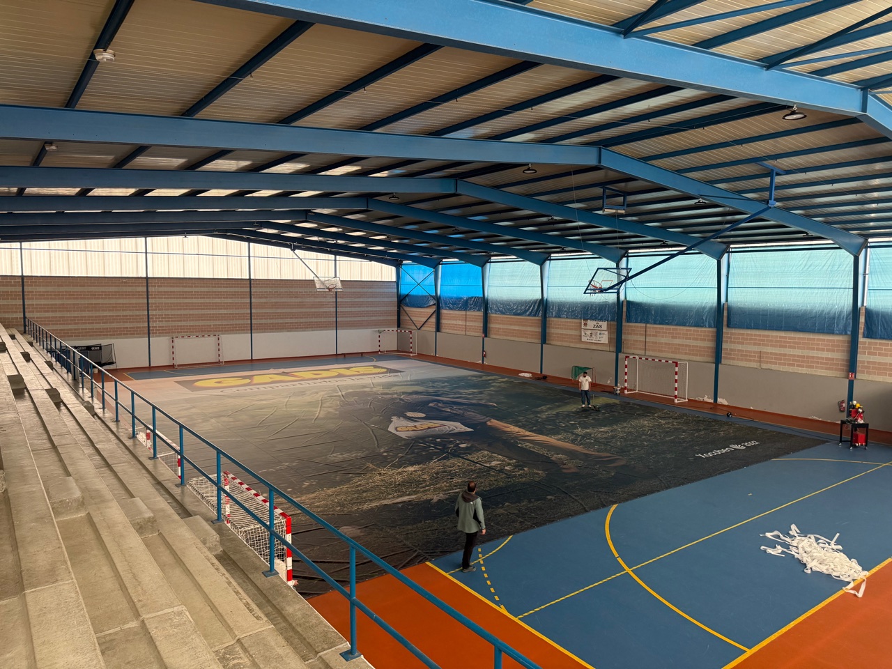 La lona de 752 m² extendida sobre la pista del pabellón de Zas, con la imagen del peregrino del Camino visible